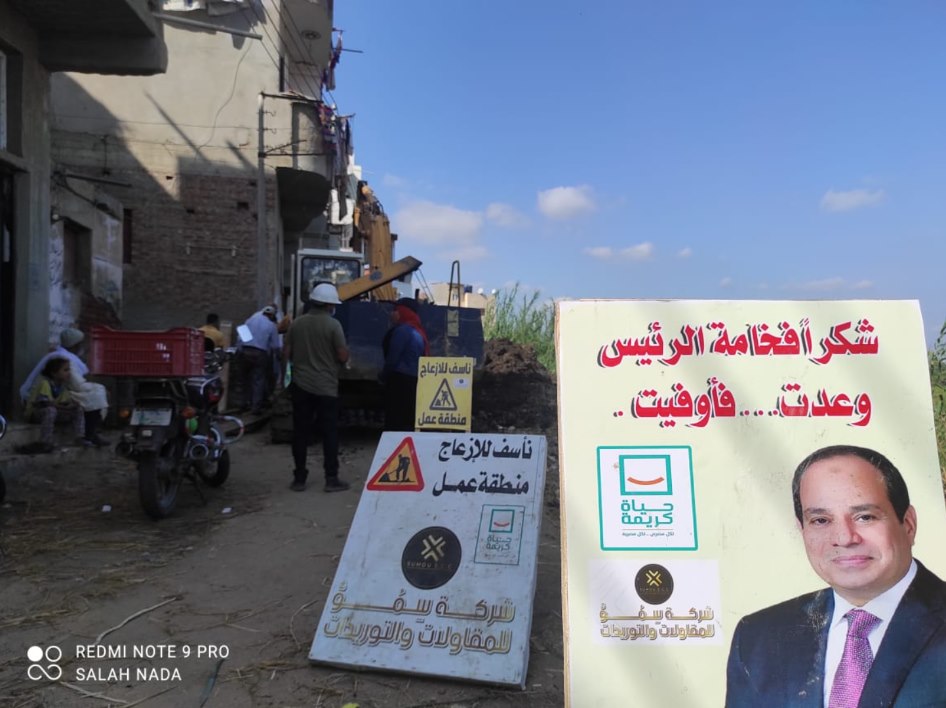 موقع تنفيذ داخل القرية مع لوحات المبادرة ولافتات منطقة العمل